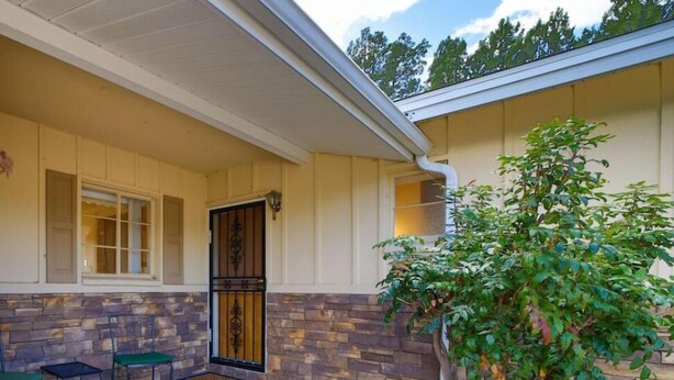 A covered patio area with stone walls, a small tree, and two chairs. - Stay and Play! *Golfers Retreat *Budget Friendly (Prescott)