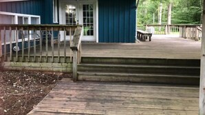 Ett litet blått hus med en träveranda och en liten veranda framför huset.