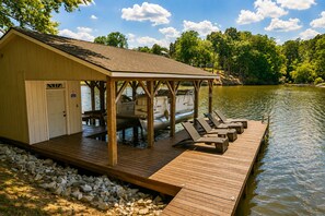 Une jetée en bois avec des chaises longues et un espace de repos abrité, au bord d’un lac.