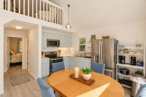 Een moderne keuken met een eethoek, met een houten tafel, stoelen en een hanglamp.