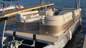 Una lancha plataforma amarrada en un muelle, con toldo, timón y zona de estar.