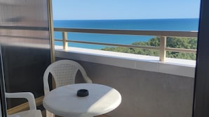 A balcony with a round table and two chairs, overlooking a clear blue sea and greenery. - Nikea Park (Varna)