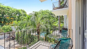 A balcony with a pool, surrounded by lush greenery and a clear sky. - El Cometa. Walk to the beach! (Tamarindo)