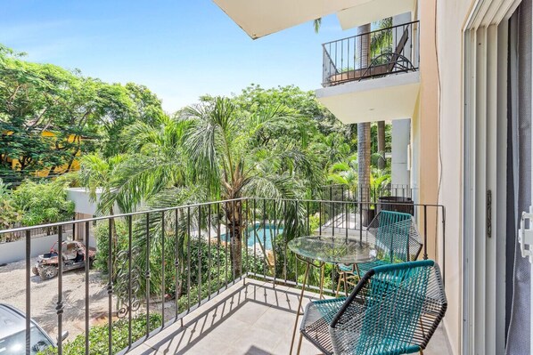 Un balcon avec une piscine, entouré d’une végétation luxuriante et surplombant un ciel dégagé.