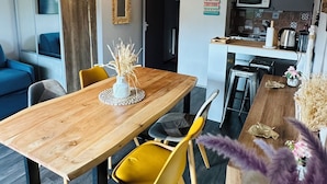 Un espace de vie moderne comprenant une table à manger en bois, des chaises jaunes et un coin cuisine équipé d’un four à micro-ondes et d’une machine à café.