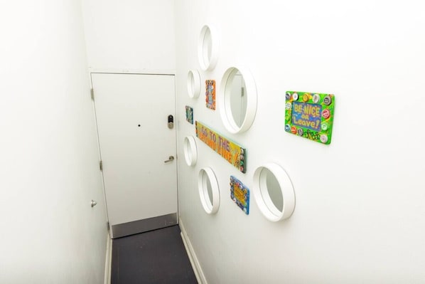 A hallway with a white door, a black floor, and several circular mirrors on the wall.