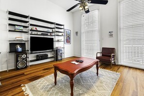 A living room with a television, speakers, a coffee table, and a leather chair.