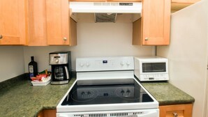 A kitchen with a stove, microwave, and coffee maker. - Creole Cottage, Designer, Balcony (New Orleans)