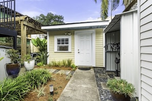 A residential property with a front door, a small porch, and a garden with various plants.