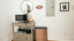 A kitchenette with a microwave, a trash bin, a cabinet with a sink, and a mirror. - Creole Cottage, Designer, Balcony (New Orleans)