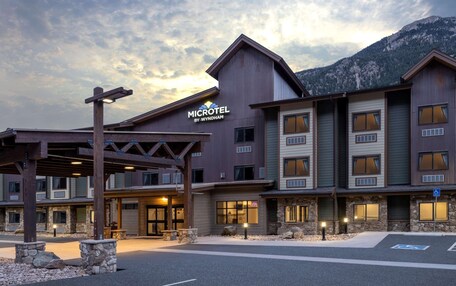 A Microtel by Wyndham hotel with a modern design, featuring multiple floors and a mountain backdrop.