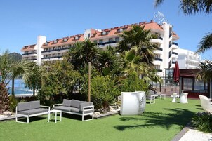 Un hotel con piscina en la azotea, mobiliario de exterior y abundante vegetación.