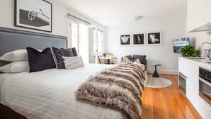 A modern bedroom with a large bed, a desk, and a view of the outdoors. - Designer Studio in Grand Manor 20 min From Sydney (Lewisham)