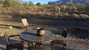 Eine Terrassensitzgelegenheit im Freien mit einem runden Tisch, Stühlen, einer dekorativen Vase und Blick auf eine gebirgige Landschaft.
