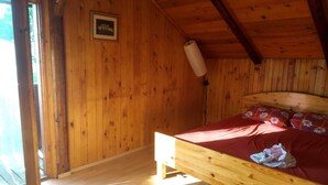 A wooden cabin room with a bed, a framed picture on the wall, and a window. - Villa in Nature (Mozirje)