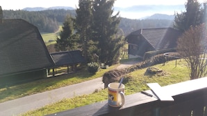 A view from a window overlooking a rural landscape with a wooden bench, a mug, and a notepad on the ledge. - Villa in Nature (Mozirje)