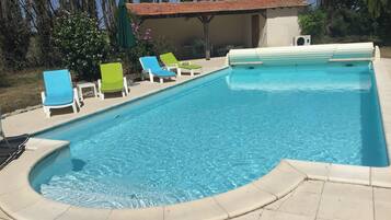 Een verwarmd zwembad, ligstoelen bij het zwembad