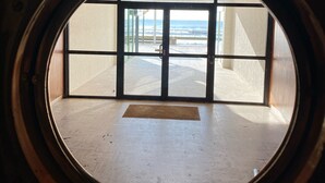 A circular window with a view of a beach and a building structure. - Waterfront apartment in St Gilles Croix de Vie (Saint-Gilles-Croix-de-Vie)