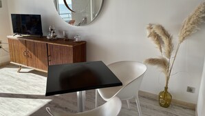 A modern living room with a round mirror, a wooden cabinet, a flat-screen TV, a white chair, and a vase with pampas grass. - Waterfront apartment in St Gilles Croix de Vie (Saint-Gilles-Croix-de-Vie)