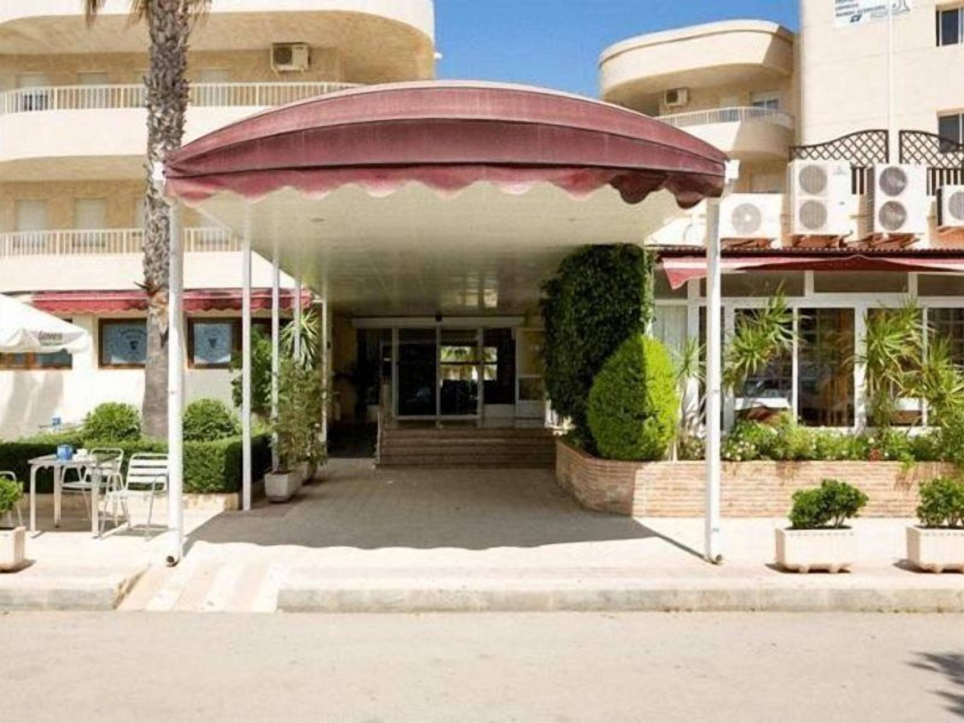 L'ingresso di un hotel con un portico coperto, gradini che conducono all'entrata e piante in vaso.