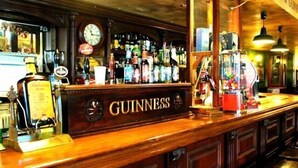A bar with a Guinness sign, a clock, and various bottles. - Riviera Beach Apartments (Pilar de la Horadada)