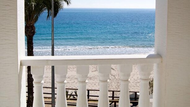 A balcony with a view of the ocean through an arched window. - Riviera Beach Apartments (Pilar de la Horadada)