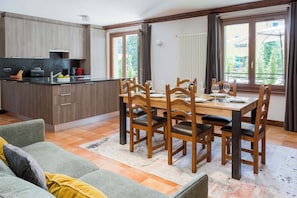 Une cuisine moderne avec un coin repas, des chaises en bois, une table et un canapé.