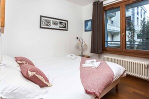 Ein Hotelzimmer mit Bett, einem Fenster mit Vorhängen, einem Heizkörper und einer Wandlampe.