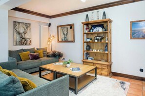 A living room with a sofa, a coffee table, a bookshelf, and decorative items.
