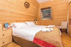 Una habitación con paneles de madera, una cama, una mesita de noche, una silla y una ventana con un cuadro.