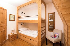 A bunk bed room with a desk, chair, and a mirror.