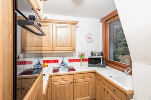A kitchen with wooden cabinets, a microwave, and a window with a view. - Ski at Le Paradis 18 & 18b apt, Chamonix All Year (Chamonix)