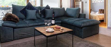 Ein modernes Wohnzimmer mit einer Eckcouch, einem Holztisch und einer Flasche Merlot-Wein.