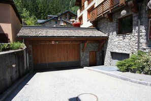 Un bâtiment à la façade en pierre, avec une porte de garage en bois et un objet sphérique rouge sur le toit.