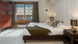 Camera d'albergo con un letto grande, un armadio in legno, una finestra con tende e vista sugli edifici.