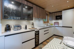 Une cuisine moderne avec des meubles blancs, un grille-pain en acier inoxydable, une machine à café et un four à micro-ondes.