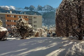 Une rue enneigée, avec des bâtiments et des montagnes en arrière-plan.