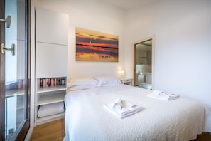 Habitació d'hotel amb un llit, un quadre, una estanteria i un mirall.