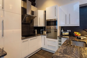 A modern kitchen with white cabinets, a built-in oven, a stovetop, and a toaster.