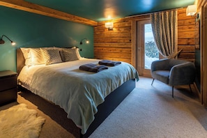 Une chambre à coucher avec un lit, des lampes de chevet, une chaise et une vue par la fenêtre.