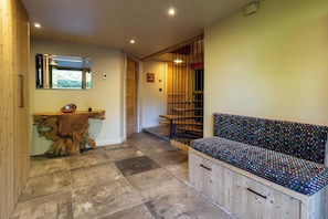 Un couloir avec un banc en bois, un miroir et une armoire en bois.