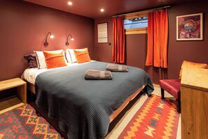 A hotel room with a large bed, two bedside tables, a desk, and a chair.