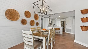 Eine moderne Küche mit weißen Schränken, einer zentralen Kochinsel und einem Essbereich mit Holztisch und Stühlen.
