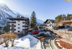 A mountain resort with multi-story buildings, a snow-covered landscape, and a red vehicle parked on a street.
