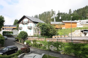 A two-story building with a balcony, surrounded by greenery and a stone wall. - Le Brevent apartment, Skiing, Chamonix All Year (Chamonix)