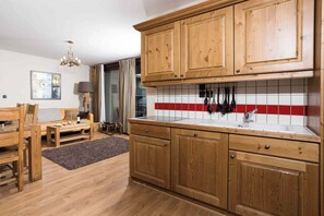 A kitchen with wooden cabinets, a tiled backsplash, and a dining area with a table and chairs.