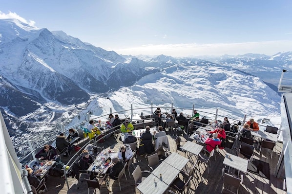 A dining area with tables and chairs, overlooking a snowy mountain landscape.