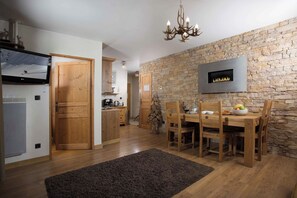 Een moderne keuken met een stenen muur, houten kastjes en een eethoek met een tafel en stoelen.