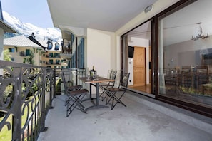 Un balcon avec une table et des chaises, une bouteille de champagne et une vue sur une montagne.