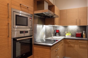 Una cocina moderna con electrodomésticos de acero inoxidable, armarios de madera y un lavamanos integrado.
